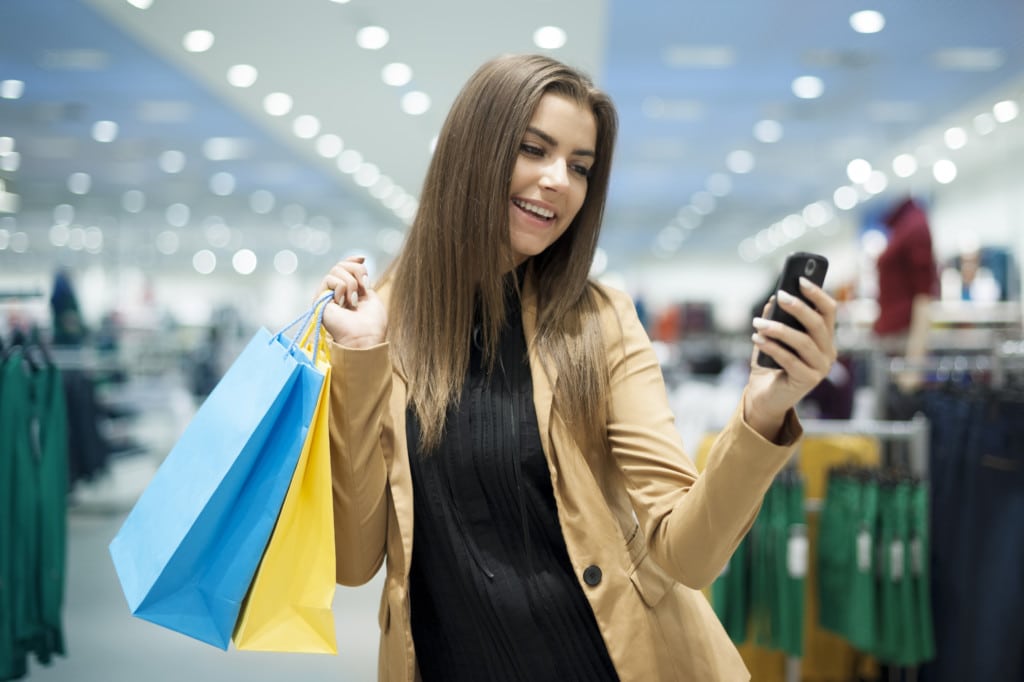 Cheerful female shopper texting on mobile phone Cheerful female shopper texting on mobile phone